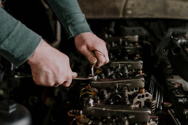 Person Holding a Wrench Repairing the Engine